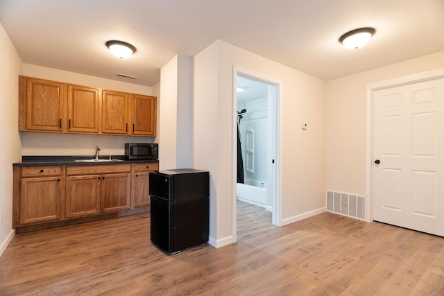 kitchen with black fridge, sink, and light hardwood / wood-style floors