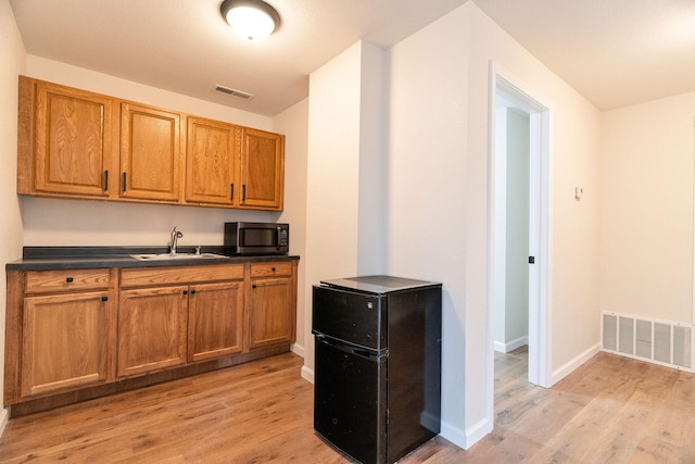 kitchen featuring light hardwood / wood-style floors, fridge, and sink