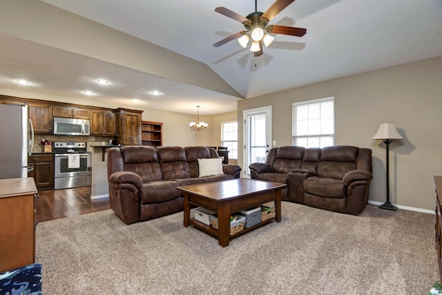 living room with ceiling fan with notable chandelier, dark hardwood / wood-style flooring, and lofted ceiling