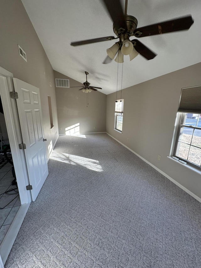 carpeted spare room featuring a wealth of natural light, ceiling fan, and vaulted ceiling