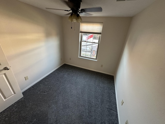 spare room featuring dark colored carpet and ceiling fan