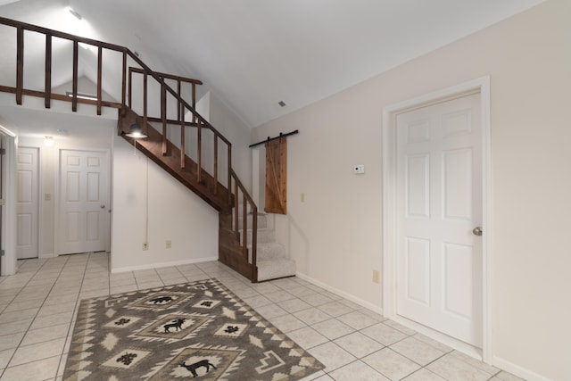 interior space with a barn door, lofted ceiling, and light tile patterned floors