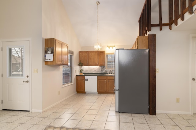 kitchen featuring high vaulted ceiling, white dishwasher, stainless steel fridge, light tile patterned floors, and decorative light fixtures