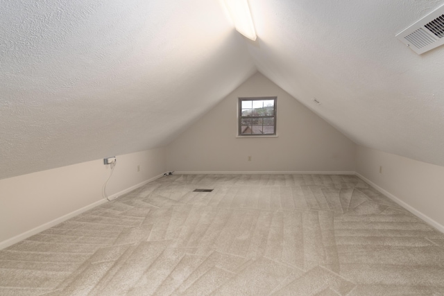 bonus room with a textured ceiling, light colored carpet, and vaulted ceiling