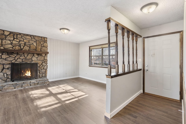 foyer entrance featuring dark hardwood / wood-style floors, a stone fireplace, and a textured ceiling