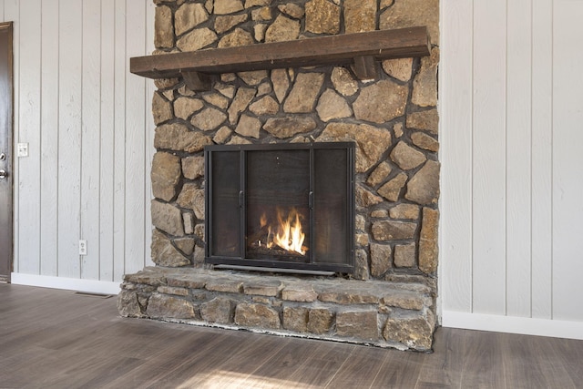 details featuring hardwood / wood-style floors, a stone fireplace, and wood walls