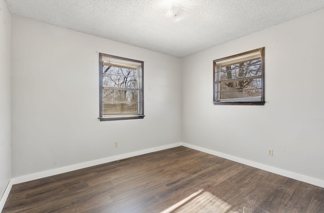 spare room featuring a textured ceiling and dark hardwood / wood-style floors