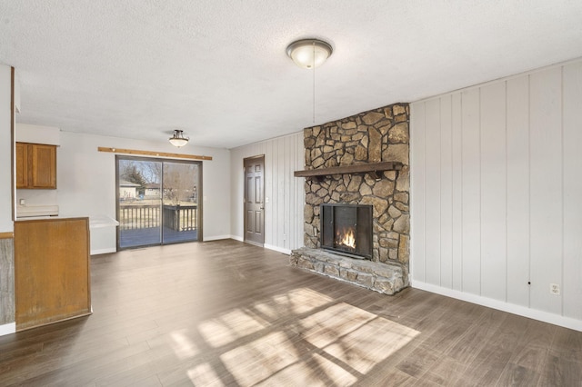 unfurnished living room featuring a fireplace, a textured ceiling, and dark hardwood / wood-style floors