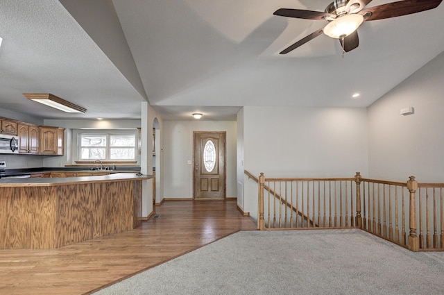 kitchen with sink, vaulted ceiling, hardwood / wood-style flooring, ceiling fan, and range