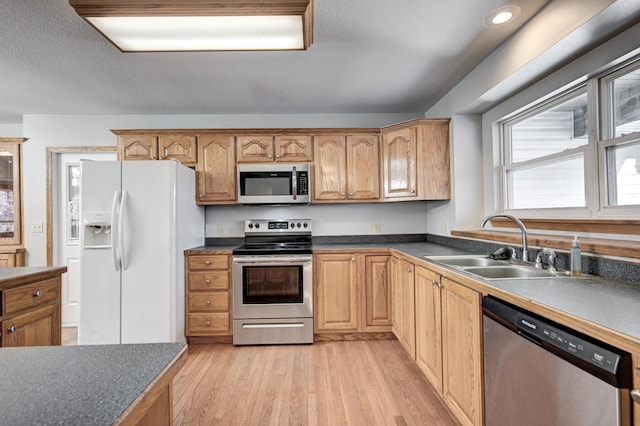 kitchen featuring a textured ceiling, stainless steel appliances, light hardwood / wood-style flooring, and sink