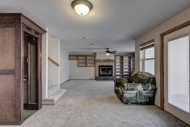 living room featuring a textured ceiling, carpet floors, and ceiling fan