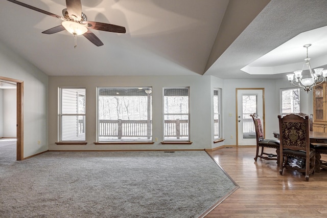 living room with vaulted ceiling, a wealth of natural light, ceiling fan with notable chandelier, and hardwood / wood-style flooring