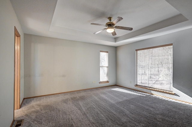 empty room featuring a tray ceiling, ceiling fan, and light colored carpet