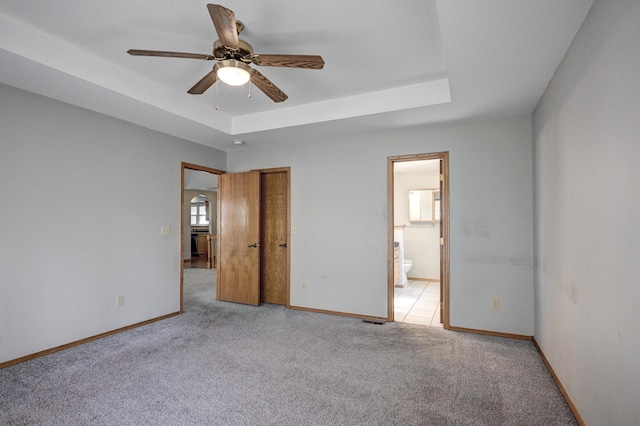 unfurnished bedroom with a tray ceiling, ceiling fan, and light colored carpet