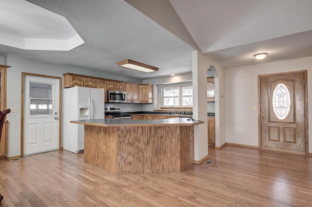 kitchen with appliances with stainless steel finishes, a textured ceiling, sink, a center island, and light hardwood / wood-style floors