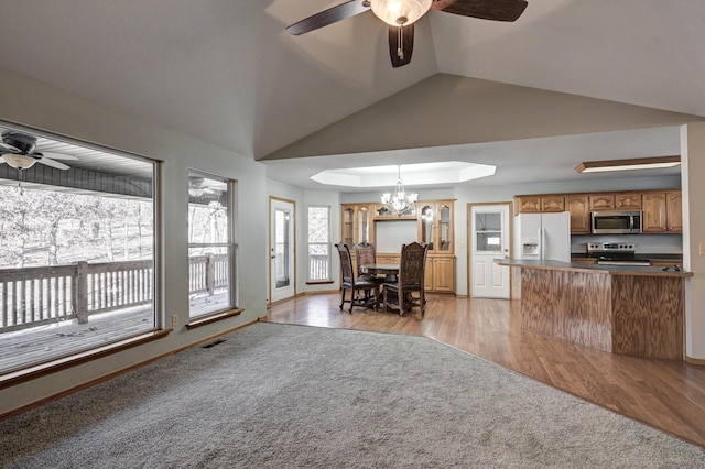 kitchen featuring hanging light fixtures, stainless steel appliances, kitchen peninsula, light hardwood / wood-style floors, and vaulted ceiling