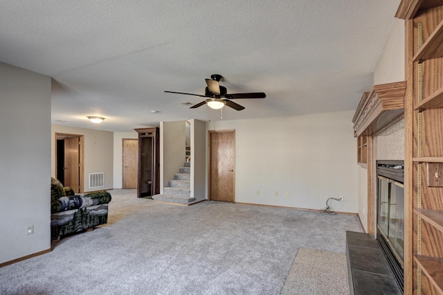 carpeted living room with a tiled fireplace, ceiling fan, and a textured ceiling