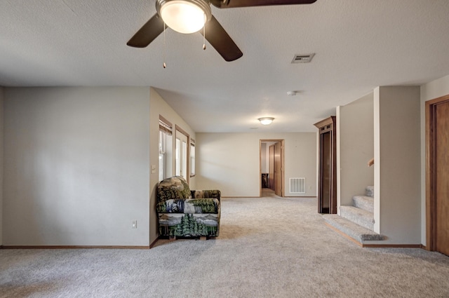 living area featuring light carpet, a textured ceiling, and ceiling fan