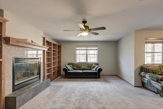 carpeted living room with a tile fireplace, ceiling fan, and a textured ceiling