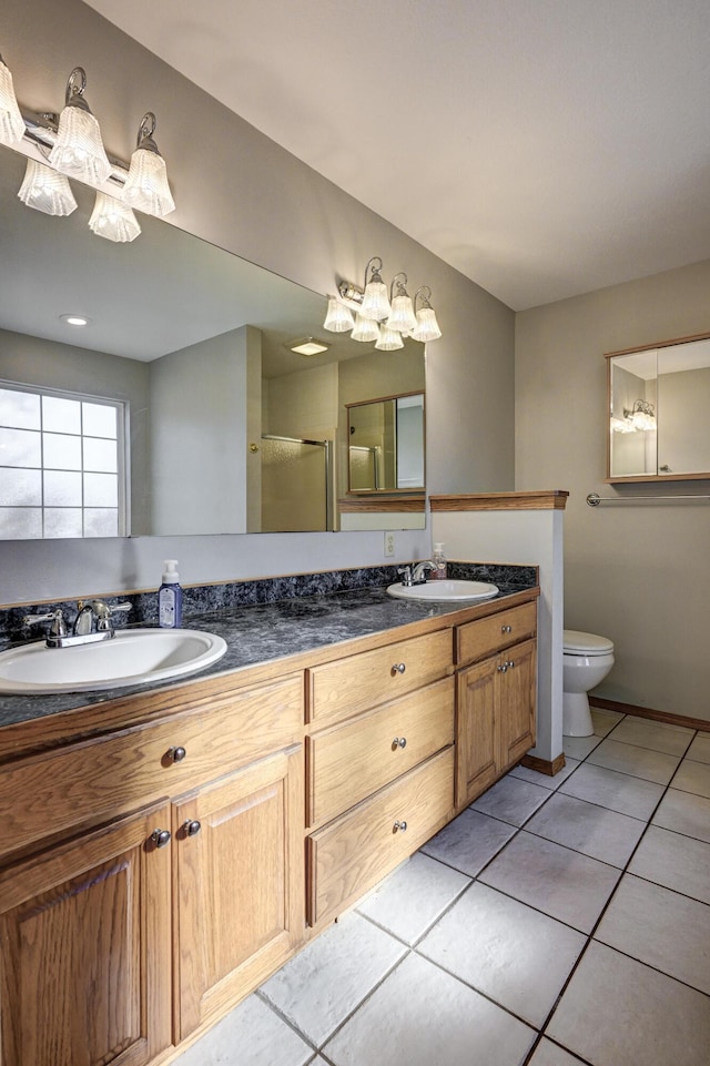 bathroom with tile patterned flooring, vanity, toilet, and a shower with door