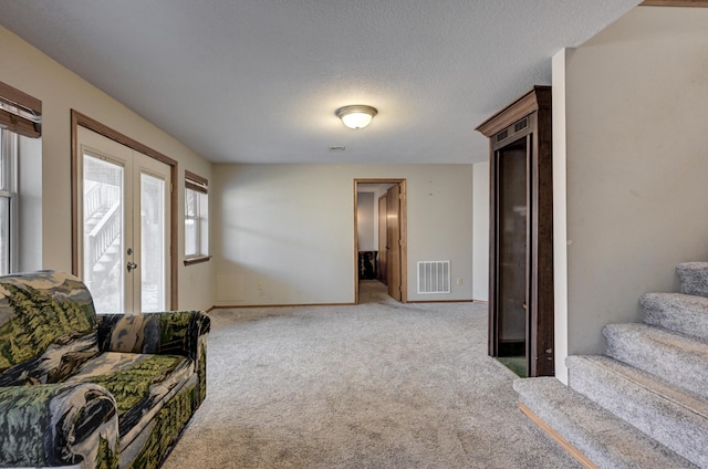 carpeted living room with french doors and a textured ceiling