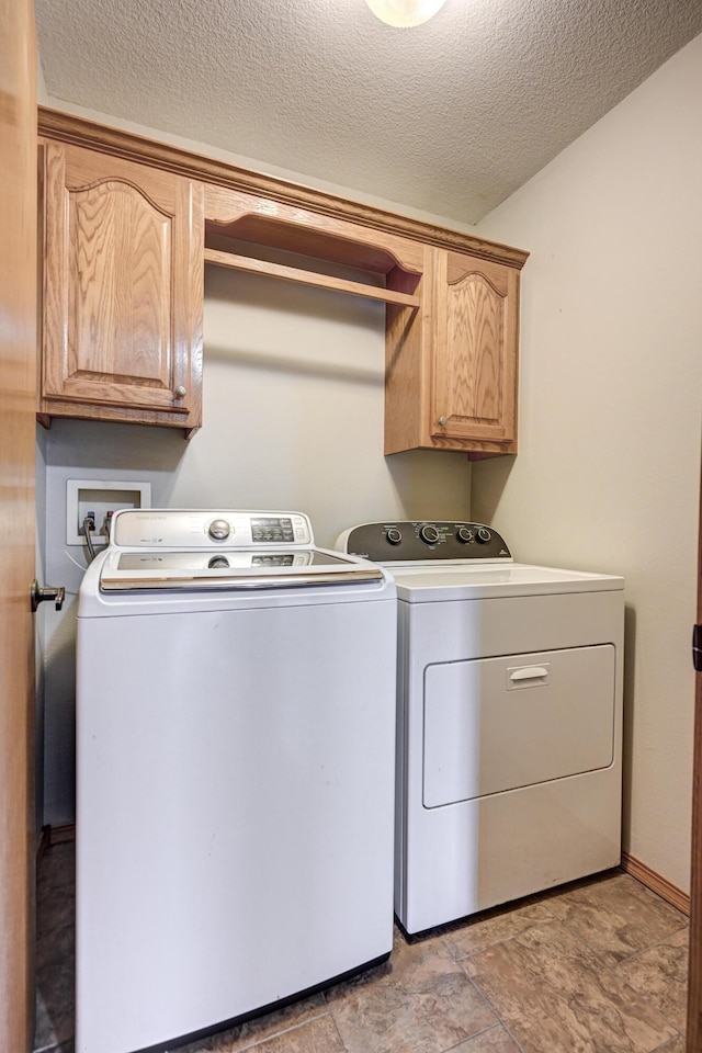 laundry area featuring washer and dryer, cabinets, and a textured ceiling