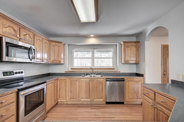 kitchen with sink, light hardwood / wood-style flooring, a textured ceiling, and appliances with stainless steel finishes