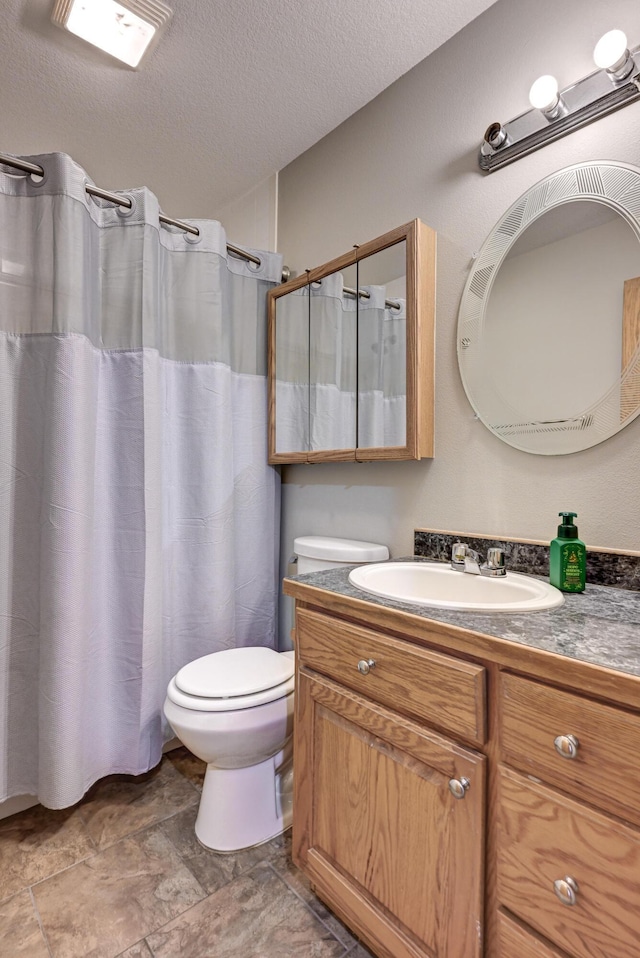 bathroom featuring vanity, toilet, and a textured ceiling