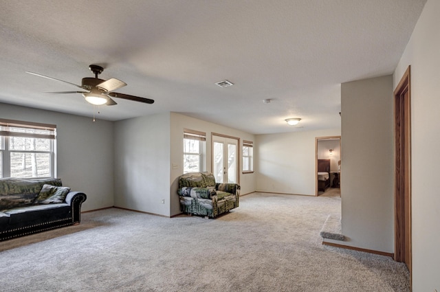 living room featuring light carpet, a textured ceiling, a wealth of natural light, and ceiling fan