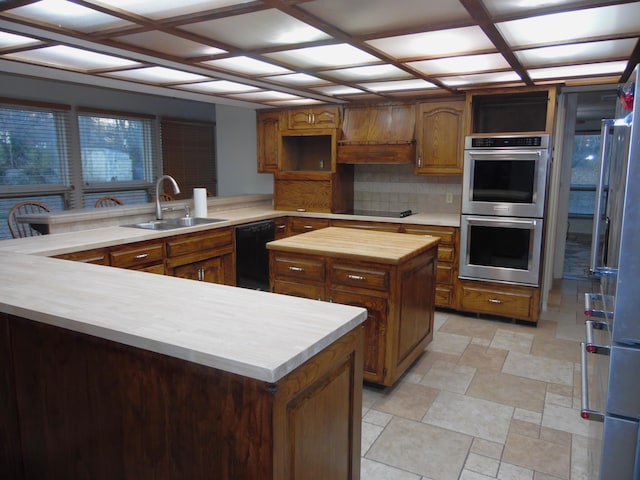 kitchen featuring kitchen peninsula, appliances with stainless steel finishes, backsplash, sink, and a center island