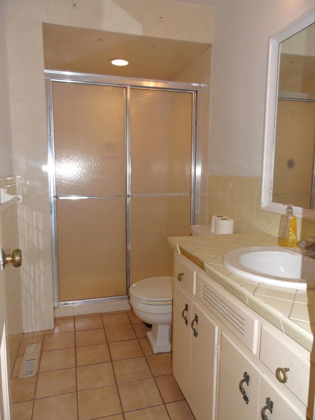 bathroom with tile patterned floors, vanity, a shower with shower door, and toilet