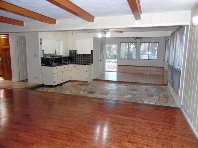 unfurnished living room with beamed ceiling, ceiling fan, and light hardwood / wood-style flooring