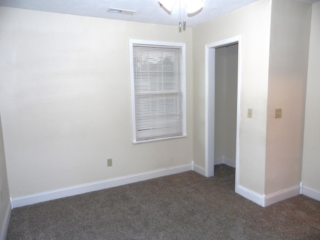 unfurnished room featuring ceiling fan and dark colored carpet