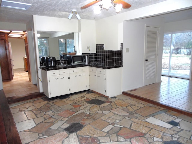 kitchen with white cabinets, tile counters, decorative backsplash, and a textured ceiling