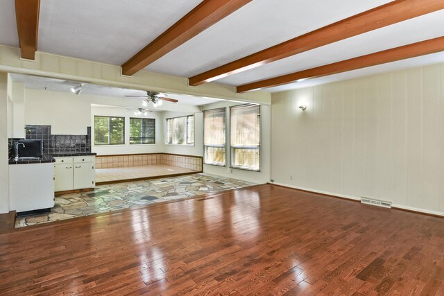 3011 E Lamonta Dr, Springfield, MO 65804 - unfurnished living room featuring wood finished floors, beam ceiling, and a ceiling fan