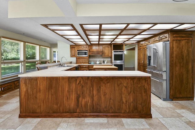 3011 E Lamonta Dr, Springfield, MO 65804 - kitchen with stainless steel appliances, a peninsula, stone tile floors, coffered ceiling, and light countertops
