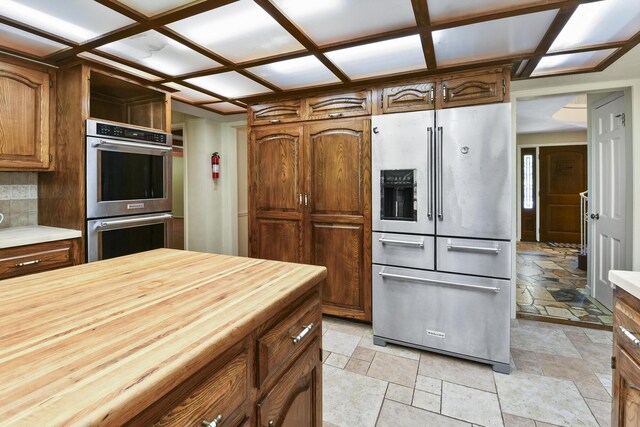 3011 E Lamonta Dr, Springfield, MO 65804 - kitchen with appliances with stainless steel finishes, stone tile flooring, butcher block countertops, and brown cabinets