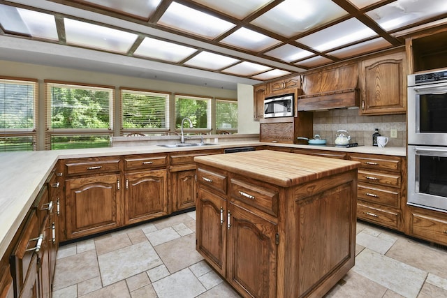 3011 E Lamonta Dr, Springfield, MO 65804 - kitchen with appliances with stainless steel finishes, decorative backsplash, wood counters, stone tile floors, and a kitchen island