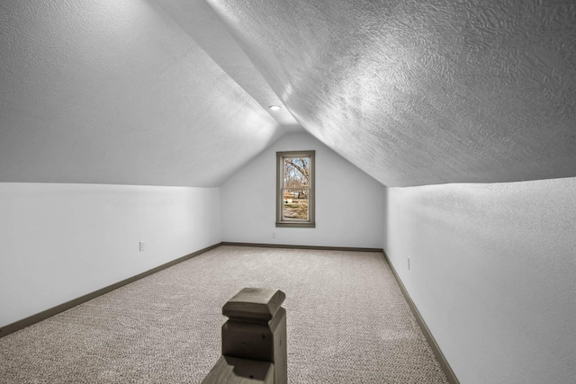 additional living space featuring vaulted ceiling, carpet floors, and a textured ceiling