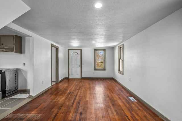 unfurnished living room with dark hardwood / wood-style flooring and a textured ceiling