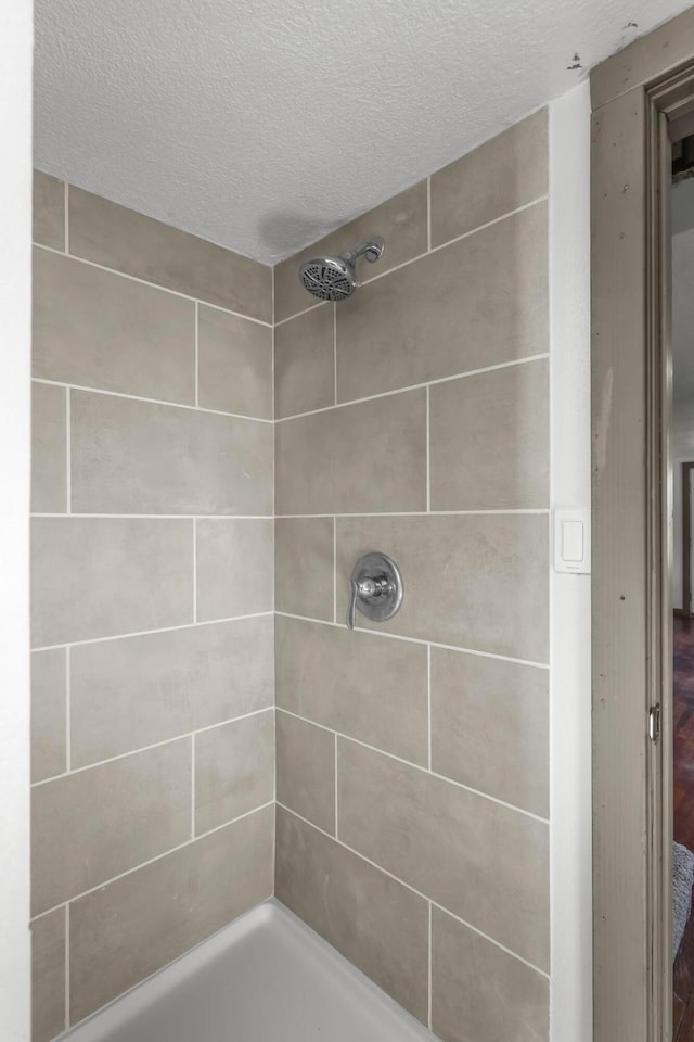 bathroom featuring a textured ceiling and tiled shower