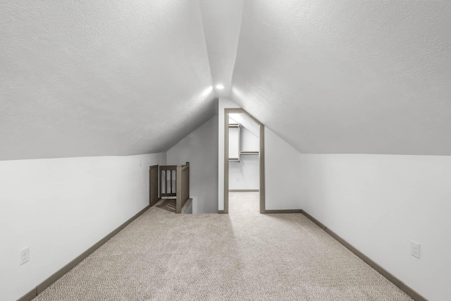 additional living space featuring carpet, lofted ceiling, and a textured ceiling