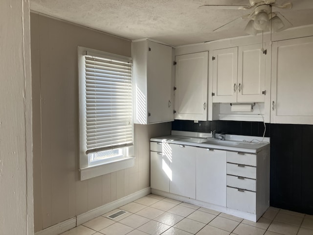 kitchen with white cabinets, ceiling fan, light tile patterned flooring, and a textured ceiling