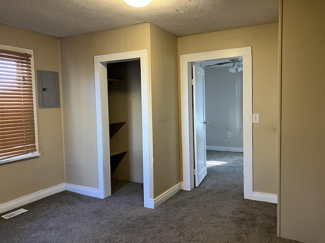 hallway featuring dark colored carpet, a textured ceiling, and electric panel