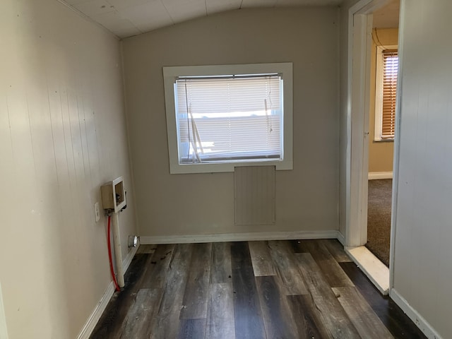 empty room with dark hardwood / wood-style flooring, lofted ceiling, and wood walls