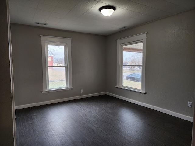 unfurnished room with a healthy amount of sunlight, ornamental molding, and dark wood-type flooring