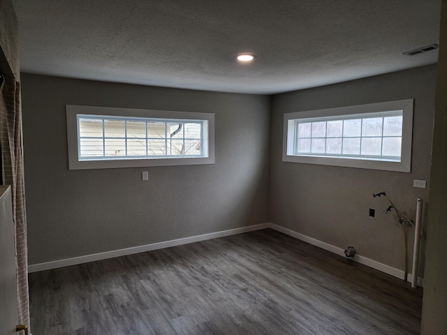 spare room featuring a textured ceiling and dark wood-type flooring