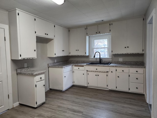 kitchen with white cabinets, light hardwood / wood-style flooring, and sink