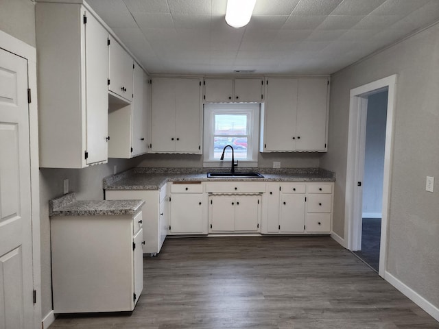 kitchen with white cabinets, hardwood / wood-style flooring, and sink