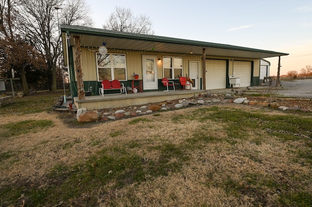 view of front of house featuring a yard, a porch, and a garage